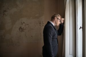 Desperate evicted male entrepreneur standing near window