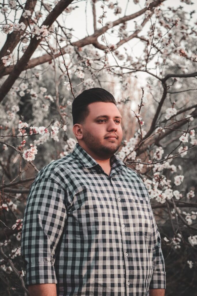 a man standing in front of a tree with white flowers